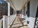 Inviting front porch with rocking chairs, offering a relaxing view of the wooded area at 38899 Dalton Ln, Albemarle, NC 28001