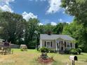 Quaint cottage with gray siding, red shutters, and a lush green lawn at 507 North Dr, Cherryville, NC 28021