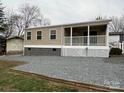 Tan manufactured home with covered porch and shed at 104 Hummingbird Dr, New London, NC 22812
