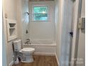 Simple bathroom with a white bathtub, toilet, and wood flooring at 3923 Old Pageland Monroe Rd, Monroe, NC 28112