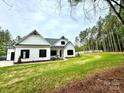 White farmhouse with black accents, nestled on a spacious lot with mature trees at 3860 Nc Hwy 200 Hwy, Concord, NC 28025
