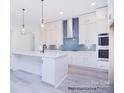 Spacious kitchen with white cabinets, blue hex tile backsplash, and island at 106 Windbluff Ct # 163, Statesville, NC 28677