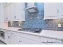 White kitchen with stainless steel appliances and blue hexagon tile backsplash at 106 Windbluff Ct # 163, Statesville, NC 28677