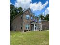 Side view of a two-story brick home with a landscaped lawn at 2044 Sweet William Dr, Harrisburg, NC 28075