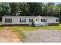 Single-wide mobile home with a gravel driveway and lush greenery at 360 Forest Hollow Dr, Statesville, NC 28677