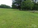 Open grassy lot with mature trees and natural landscaping at 14004 Elm St, Stanfield, NC 28163