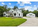 White farmhouse with attached three-car garage and expansive lawn at 5811 Kristi Ln, Midland, NC 28107