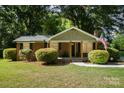 Brick ranch home with covered porch, landscaped yard, and American flag at 7714 Old Waxhaw Monroe Rd, Waxhaw, NC 28173