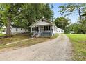 Charming white house with gray porch, gravel driveway, and spacious yard at 323 20Th St, Kannapolis, NC 28083