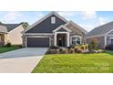 House exterior featuring stone and siding accents, a two-car garage, and a manicured lawn at 1346 Millview Ln, Matthews, NC 28104