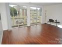 Bright living room with laminate floors and sliding glass doors leading to a balcony at 1600 H Arlyn Cir, Charlotte, NC 28213