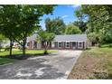 Brick ranch home with covered porch, mature trees, and a large driveway at 2009 Echo Ln, Gastonia, NC 28052