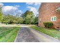 Long driveway leading to a brick home with mature trees and green lawns at 6517 Hunter Pine Ln, Charlotte, NC 28270