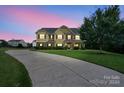 Curb appeal of a two-story house with stone accents, large windows and a long driveway at 5601 Ballenger Ct, Waxhaw, NC 28173