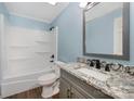 Updated bathroom with granite vanity, large mirror, and updated bathtub and shower at 4438 Old Davis Rd, Norwood, NC 28128