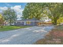 Ranch style home with gray exterior, gravel driveway, and mature trees at 335 Davidson Hwy, Concord, NC 28027