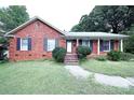 Brick ranch home with a landscaped lawn and a charming front porch at 2209 Laura Dr, Charlotte, NC 28212