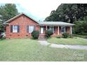 Brick ranch home with a landscaped lawn and a charming front porch at 2209 Laura Dr, Charlotte, NC 28212