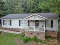 Ranch home with front porch and brick foundation, nestled in a wooded area at 394 Link Dr, Iron Station, NC 28080
