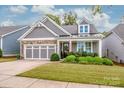 Gray house with stone accents, three-car garage, and manicured lawn at 8221 Festival Way, Charlotte, NC 28215