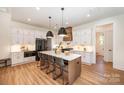 Modern kitchen with white cabinets, large island, and hardwood floors at 1029 Baylor Grv, Monroe, NC 28110