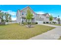 Two-story house with gray siding, a white porch, and a well-manicured lawn at 7278 Waterwheel St, Concord, NC 28025