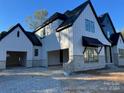 Modern farmhouse with white and black exterior, stone accents, and attached garage at 136 Castleview Ln, Mooresville, NC 28115