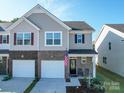 Two-story townhome with gray siding, two-car garage, and small front porch at 13111 Cottage Crest Ln, Charlotte, NC 28273