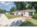 Front view of gray brick ranch home with red shutters and a spacious yard at 1300 Eureka St, Charlotte, NC 28206