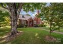 Brick home with a large tree and manicured lawn at 424 S College Ave, Newton, NC 28658