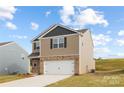 Two-story house with gray and tan siding, white garage door, and landscaped lawn at 213 Brinkley Dr # 97, Kings Mountain, NC 28086