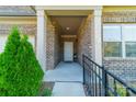 Brick home's entrance with covered porch, metal railing, and landscaping at 2014 Newstyle Way, Tega Cay, SC 29708