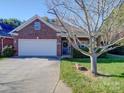 Brick ranch home with attached garage, landscaping, and wreath on door at 104 Aberdeen Dr, Troutman, NC 28166