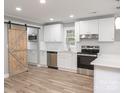 Modern kitchen featuring white cabinets, stainless steel appliances, and a barn door at 1207 S Poplar St, Landis, NC 28088