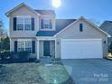 Two-story house with beige siding, white garage door, and landscaping at 1021 Meadowbrook Sw Ln, Concord, NC 28027