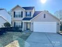 Two-story house with beige siding, white garage door, and landscaping at 1021 Meadowbrook Sw Ln, Concord, NC 28027