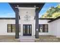 Front entry with black framed door, modern lighting, and black columns at 13306 Graymist Dr, Charlotte, NC 28215