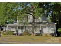 Two-story house with wrap-around porch, landscaping, and mature trees at 115 S Pearl St, Troy, NC 27371