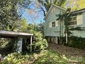 Side view of a small house with overgrown landscaping and a detached shed at 1115 Harrill St, Charlotte, NC 28205