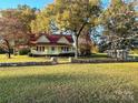 Yellow farmhouse with red roof, stone wall, and expansive lawn at 16409 Silver Rd, Oakboro, NC 28129