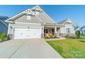 Charming house with gray siding, two-car garage, and rocking chairs on porch at 7002 Kingfisher Way, Belmont, NC 28012