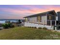 Elevated home with deck overlooking the lake at sunset at 127 Lake View Dr, New London, NC 28127