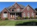 Brick house with a two-car garage, a welcoming porch, and manicured lawn at 103 Berea Baptist Church Rd, Stanfield, NC 28163
