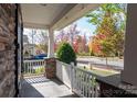 Covered porch with white railing overlooking a tree-lined street at 11840 Meetinghouse Dr, Cornelius, NC 28031