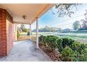 Brick home's front porch with concrete flooring, white columns, and view of a road at 24947 Nc 24/27 Hwy, Albemarle, NC 28001