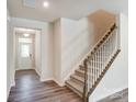 Beige carpeted staircase with wooden railing and entryway view at 14905 Tamarack Dr, Charlotte, NC 28278