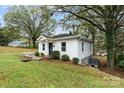 Side view of a cozy white house with a grassy yard and trees at 145 American Ne Ave, Concord, NC 28025