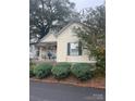 Quaint yellow cottage featuring a porch and neatly landscaped yard at 2 Elm St, Lancaster, SC 29720
