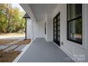 Modern front porch with gray concrete flooring and black double doors at 9000 Boyd Dr, Matthews, NC 28105