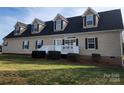 Beige house with a gray roof, dormer windows, and a white porch at 129 Burning Ln, Stony Point, NC 28678